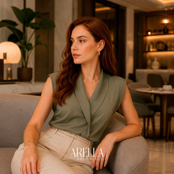 Woman in a sage sleeveless wrap top seated in a hotel lounge